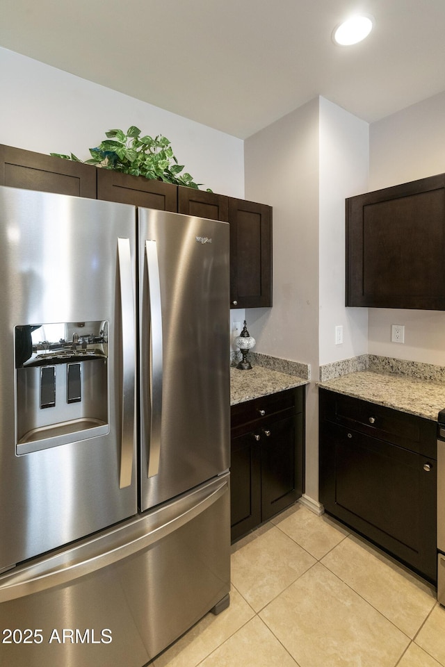 kitchen featuring light stone counters, stainless steel fridge, light tile patterned flooring, and dark brown cabinets