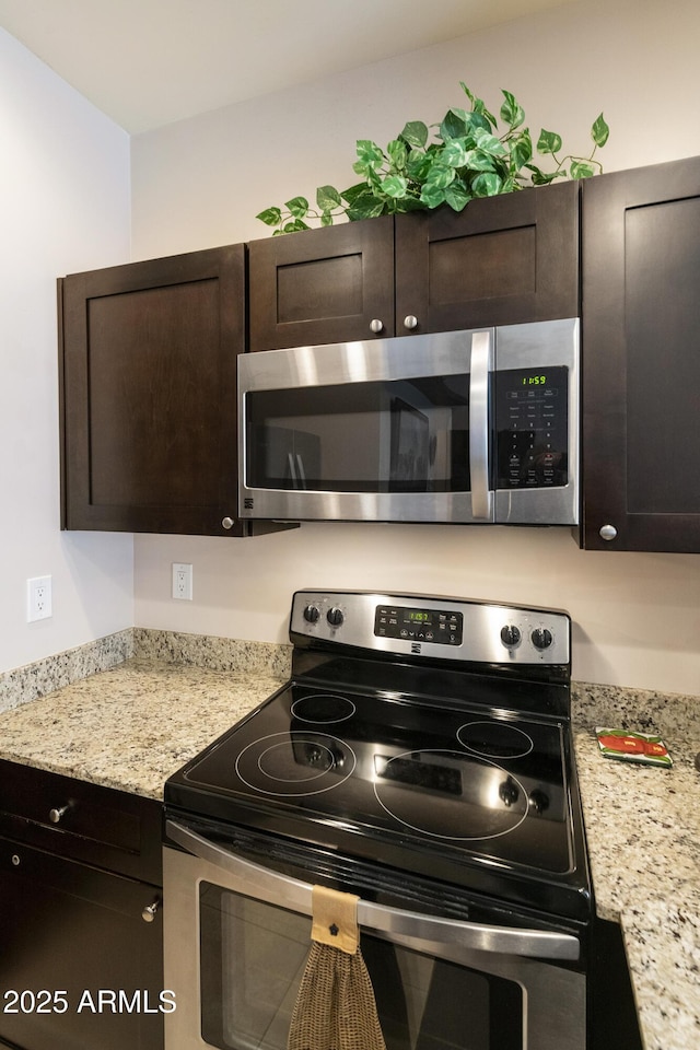 kitchen featuring dark brown cabinetry, light stone counters, and appliances with stainless steel finishes