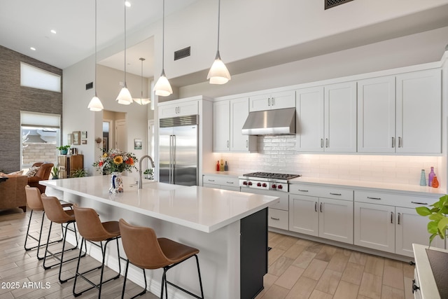 14507 N Valencia Dr, Fountain Hills, AZ 85268 - kitchen with appliances with stainless steel finishes, under cabinet range hood, a high ceiling, decorative backsplash, and a breakfast bar area