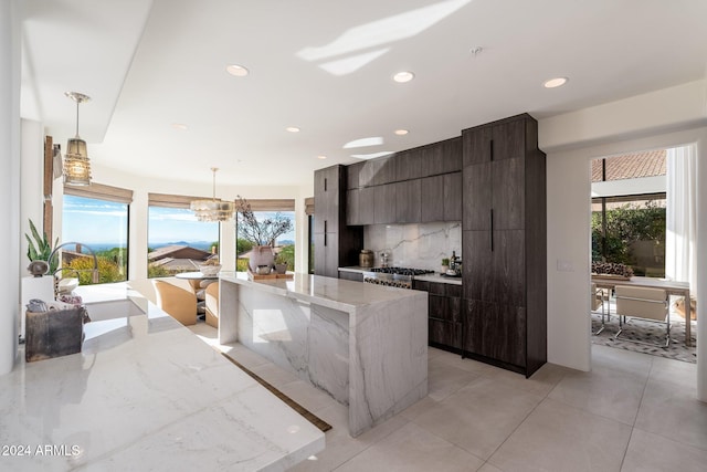 kitchen featuring hanging light fixtures, tasteful backsplash, plenty of natural light, and dark brown cabinets