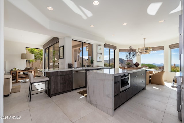 kitchen with hanging light fixtures, a notable chandelier, dark brown cabinetry, stainless steel appliances, and a spacious island