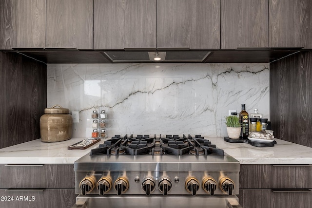 kitchen featuring tasteful backsplash, light stone countertops, stovetop, and dark brown cabinetry