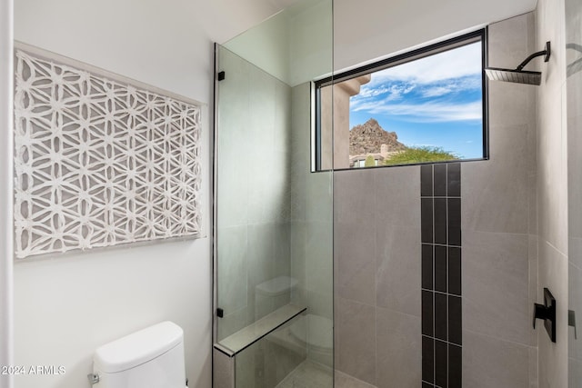 bathroom with a tile shower and toilet