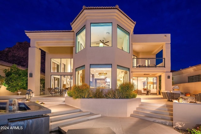 back house at night with a balcony and a patio area