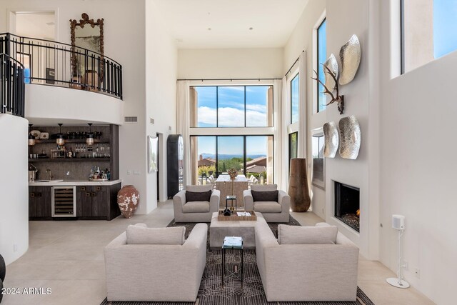 living room featuring bar, a towering ceiling, and beverage cooler