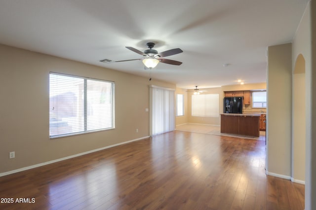 unfurnished living room featuring ceiling fan, a healthy amount of sunlight, and wood-type flooring