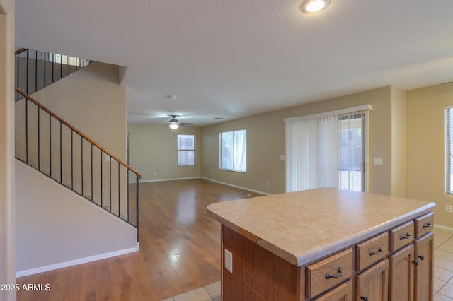 kitchen with light wood-type flooring, ceiling fan, and a center island