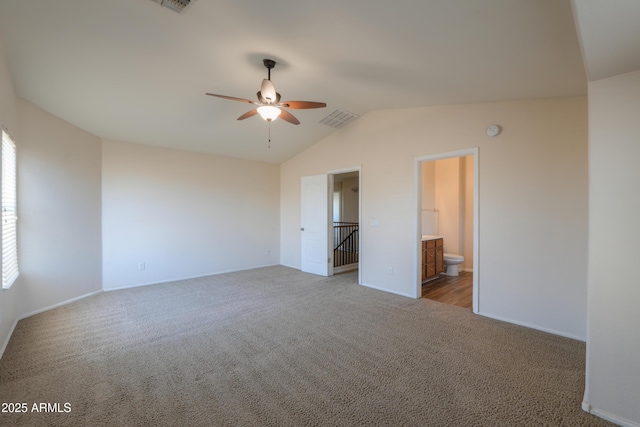 unfurnished bedroom featuring ensuite bath, light colored carpet, ceiling fan, and vaulted ceiling