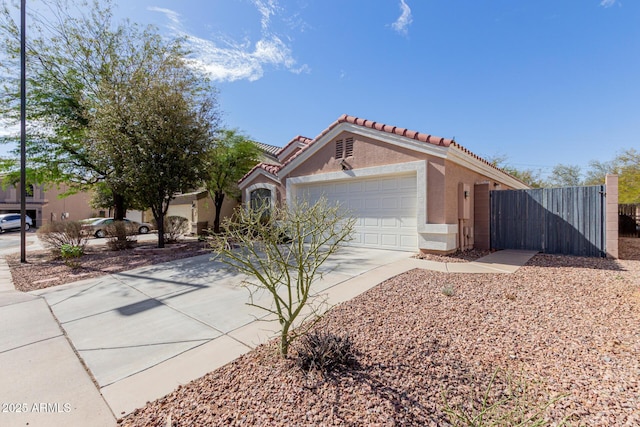 mediterranean / spanish-style house with an attached garage, concrete driveway, a tiled roof, a gate, and stucco siding