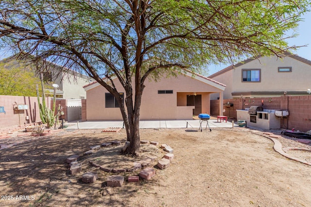 rear view of property featuring a patio, a fenced backyard, and stucco siding