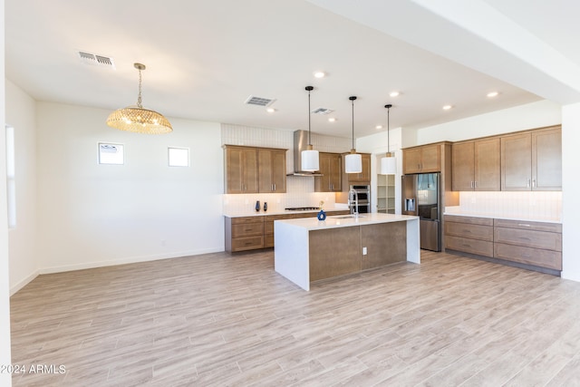 kitchen with an island with sink, tasteful backsplash, stainless steel appliances, and decorative light fixtures