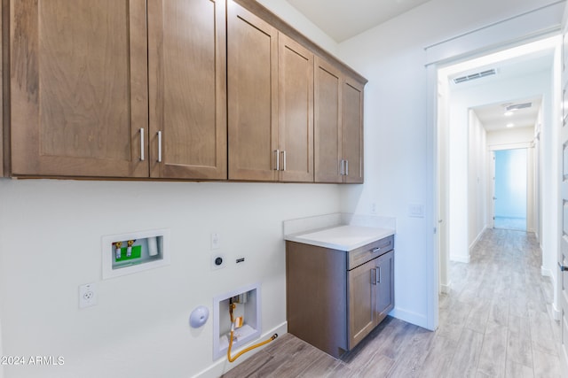 laundry area featuring electric dryer hookup, washer hookup, gas dryer hookup, light wood-type flooring, and cabinets