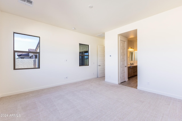 unfurnished bedroom with light colored carpet and connected bathroom