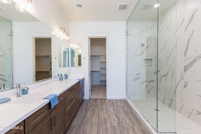 bathroom with double sink, large vanity, hardwood / wood-style flooring, and a shower with shower door