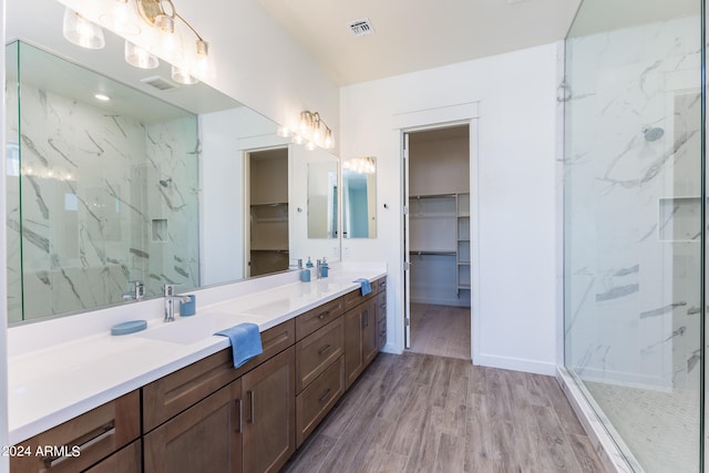 bathroom with walk in shower, dual sinks, oversized vanity, and wood-type flooring