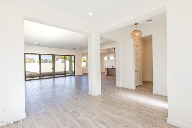 unfurnished room with light wood-type flooring and a chandelier