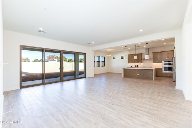 unfurnished living room featuring french doors, light hardwood / wood-style floors, and sink