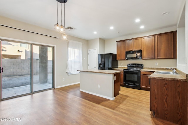 kitchen with sink, hanging light fixtures, black appliances, a kitchen island, and light wood-type flooring