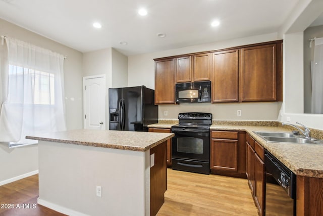 kitchen featuring light hardwood / wood-style floors, sink, a kitchen island, and black appliances