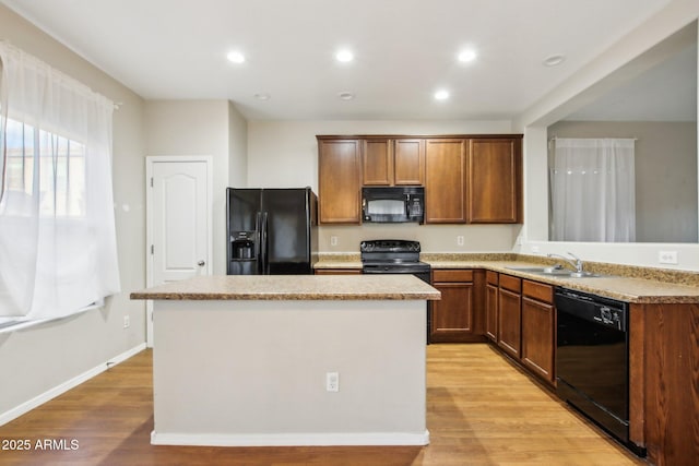 kitchen featuring light wood-type flooring, sink, a kitchen island, and black appliances