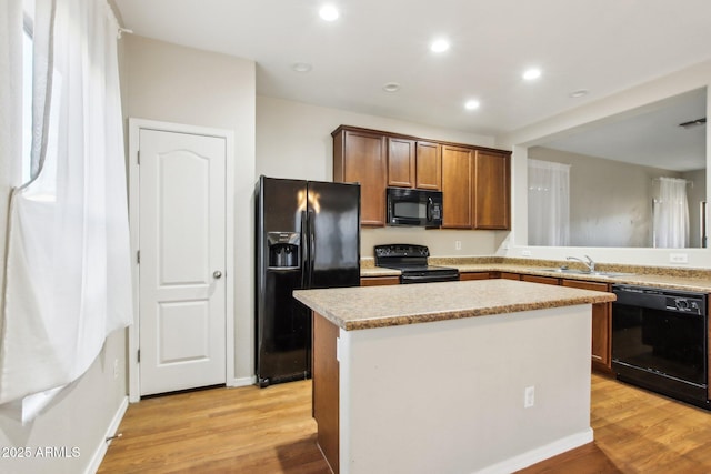 kitchen featuring sink, a center island, light hardwood / wood-style floors, and black appliances