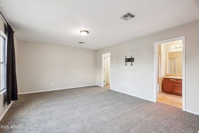 unfurnished bedroom featuring connected bathroom, sink, and light carpet