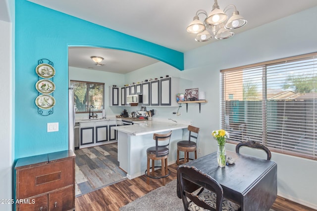 kitchen featuring a sink, appliances with stainless steel finishes, a peninsula, and dark wood finished floors