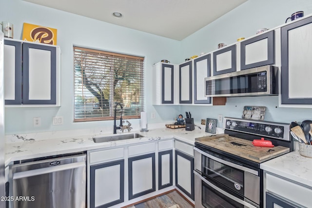 kitchen with a sink, light stone countertops, and appliances with stainless steel finishes