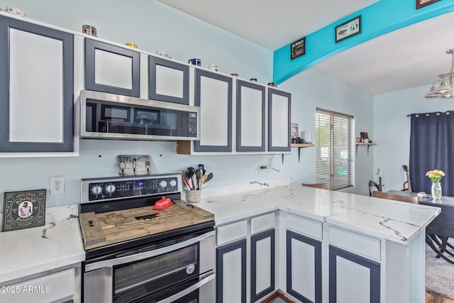 kitchen with a peninsula, decorative light fixtures, light stone countertops, and appliances with stainless steel finishes