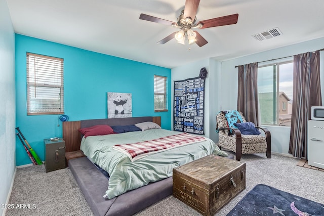 carpeted bedroom featuring visible vents, multiple windows, baseboards, and ceiling fan