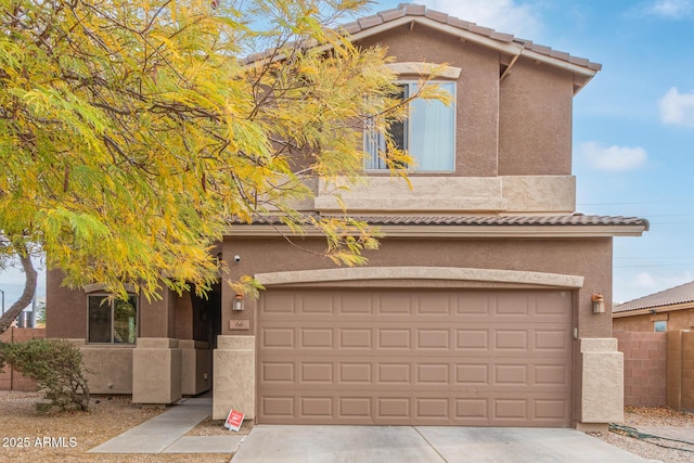 view of front of home featuring a tiled roof, stucco siding, a garage, and fence