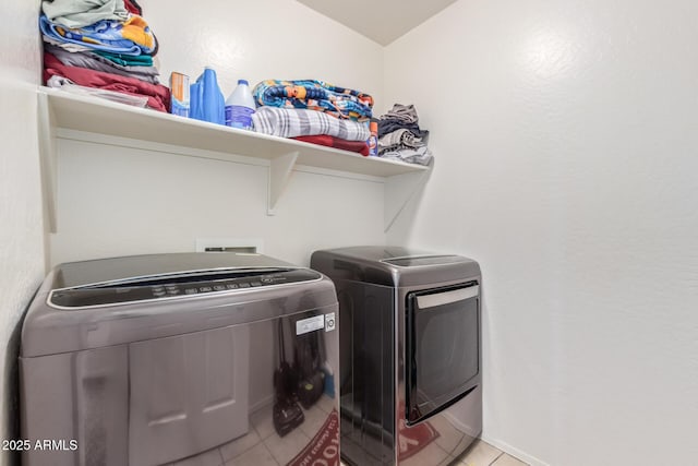 washroom with light tile patterned floors, laundry area, and washing machine and dryer