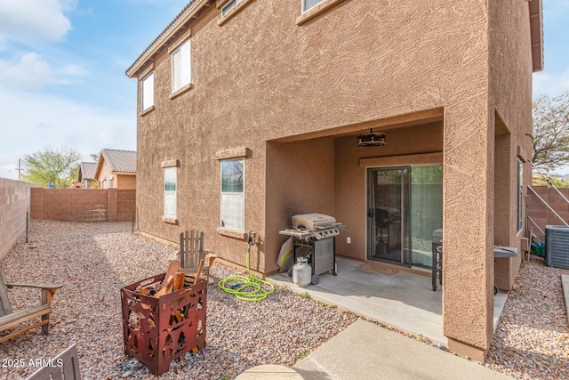 rear view of property with stucco siding, central AC unit, a fenced backyard, and a patio area