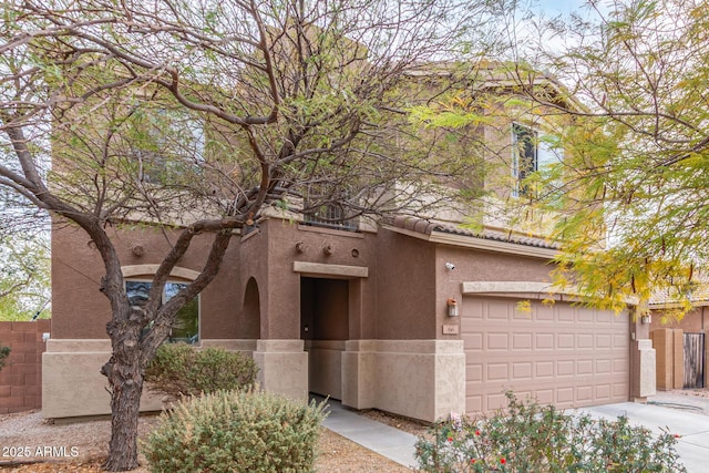 view of front of property featuring stucco siding, a tile roof, an attached garage, and fence