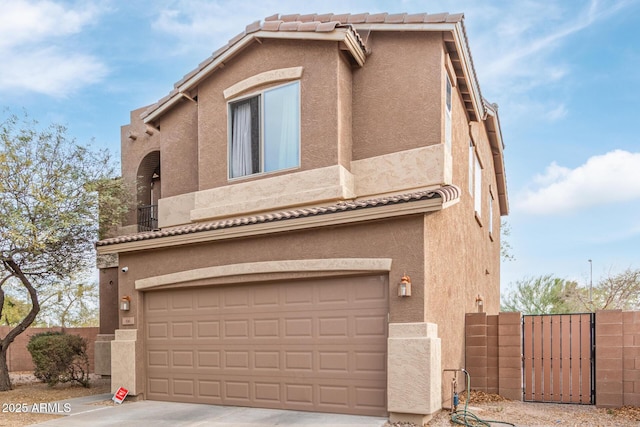 view of front of home featuring stucco siding, a garage, and a gate