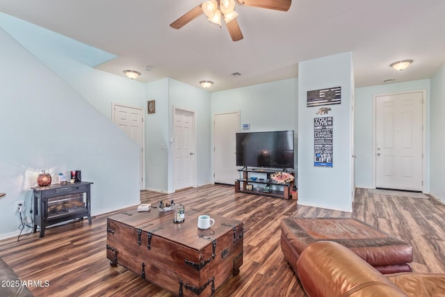 living room with visible vents, wood finished floors, baseboards, and ceiling fan