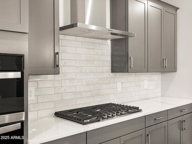 17809 W Elm St, Goodyear, AZ 85395 - kitchen with wall chimney exhaust hood, gray cabinets, stainless steel appliances, backsplash, and light stone counters