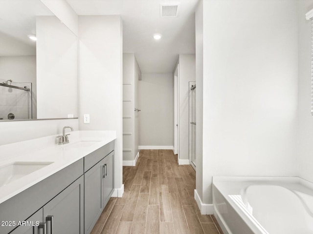 17809 W Elm St, Goodyear, AZ 85395 - bathroom with a stall shower, wood finished floors, a garden tub, double vanity, and baseboards