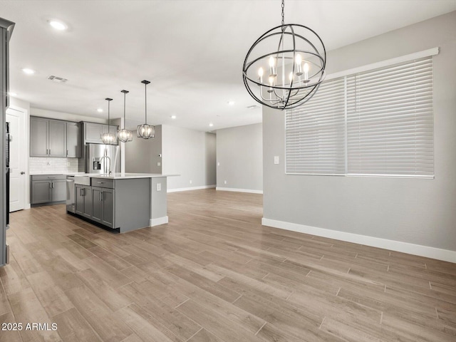 17809 W Elm St, Goodyear, AZ 85395 - kitchen featuring gray cabinetry, appliances with stainless steel finishes, a chandelier, open floor plan, and baseboards
