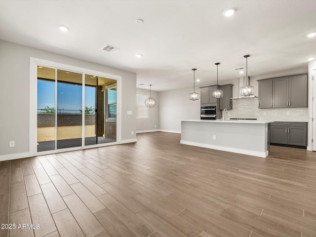 17809 W Elm St, Goodyear, AZ 85395 - unfurnished living room with baseboards, wood finished floors, recessed lighting, and a sink