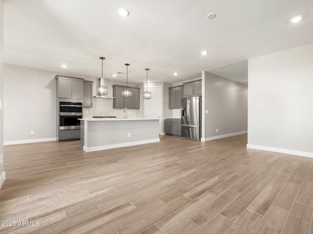 17809 W Elm St, Goodyear, AZ 85395 - kitchen with appliances with stainless steel finishes, gray cabinets, wall chimney exhaust hood, open floor plan, and recessed lighting
