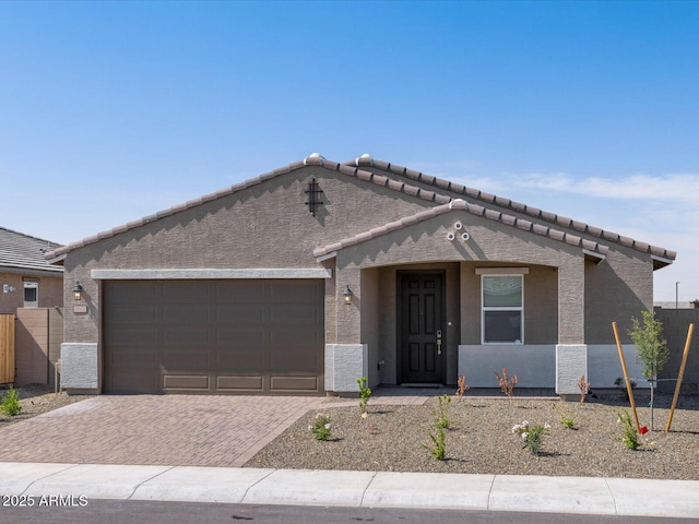 17809 W Elm St, Goodyear, AZ 85395 - view of front of home with an attached garage, decorative driveway, a tile roof, and stucco siding