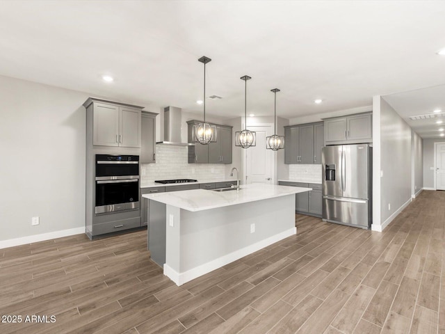 17809 W Elm St, Goodyear, AZ 85395 - kitchen with stainless steel appliances, gray cabinetry, wall chimney exhaust hood, a sink, and light wood finished floors