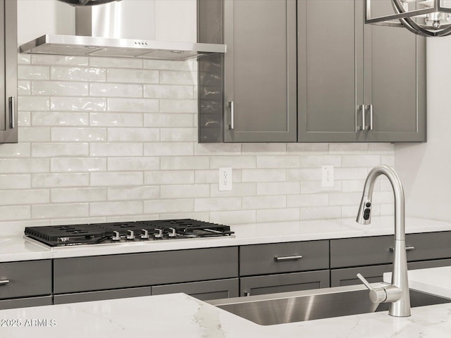 17809 W Elm St, Goodyear, AZ 85395 - kitchen featuring gray cabinetry, wall chimney exhaust hood, backsplash, and stainless steel gas stovetop
