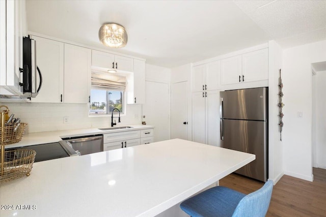 kitchen featuring white cabinets, dark wood-type flooring, sink, appliances with stainless steel finishes, and a kitchen bar