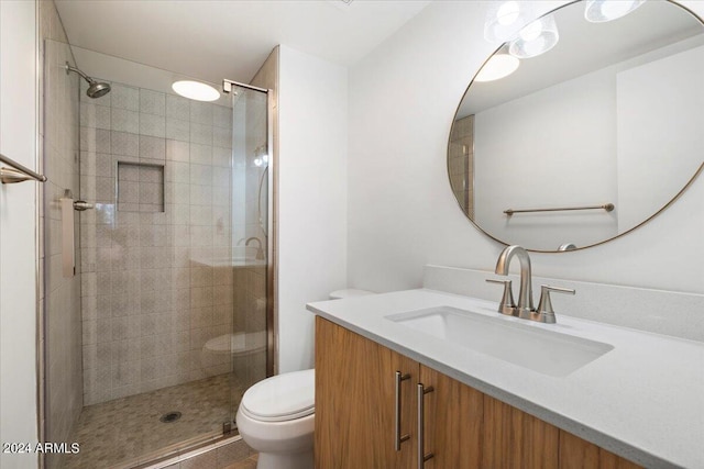 bathroom featuring tile patterned floors, vanity, toilet, and a shower with shower door