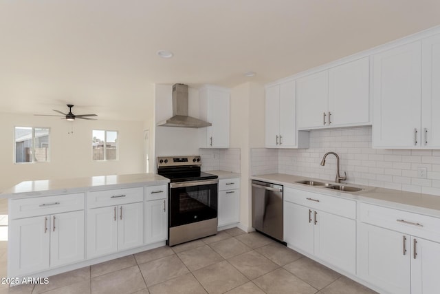 kitchen with sink, white cabinetry, stainless steel appliances, kitchen peninsula, and wall chimney exhaust hood