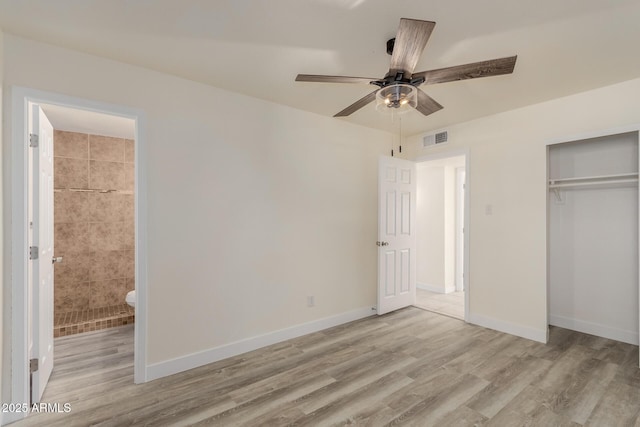 unfurnished bedroom featuring ceiling fan, ensuite bathroom, a closet, and light wood-type flooring