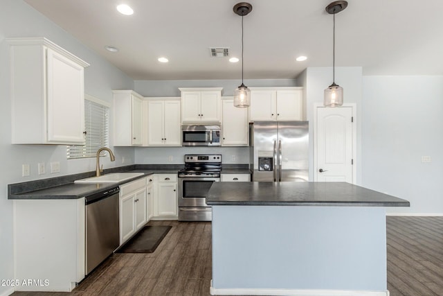 kitchen with stainless steel appliances, dark wood-type flooring, a sink, visible vents, and dark countertops