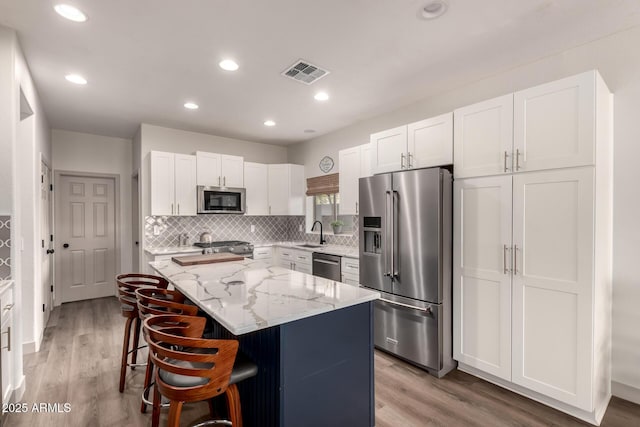 40807 N Barnum Way, Anthem, AZ 85086 - kitchen featuring appliances with stainless steel finishes, a sink, a kitchen island, light stone countertops, and white cabinets